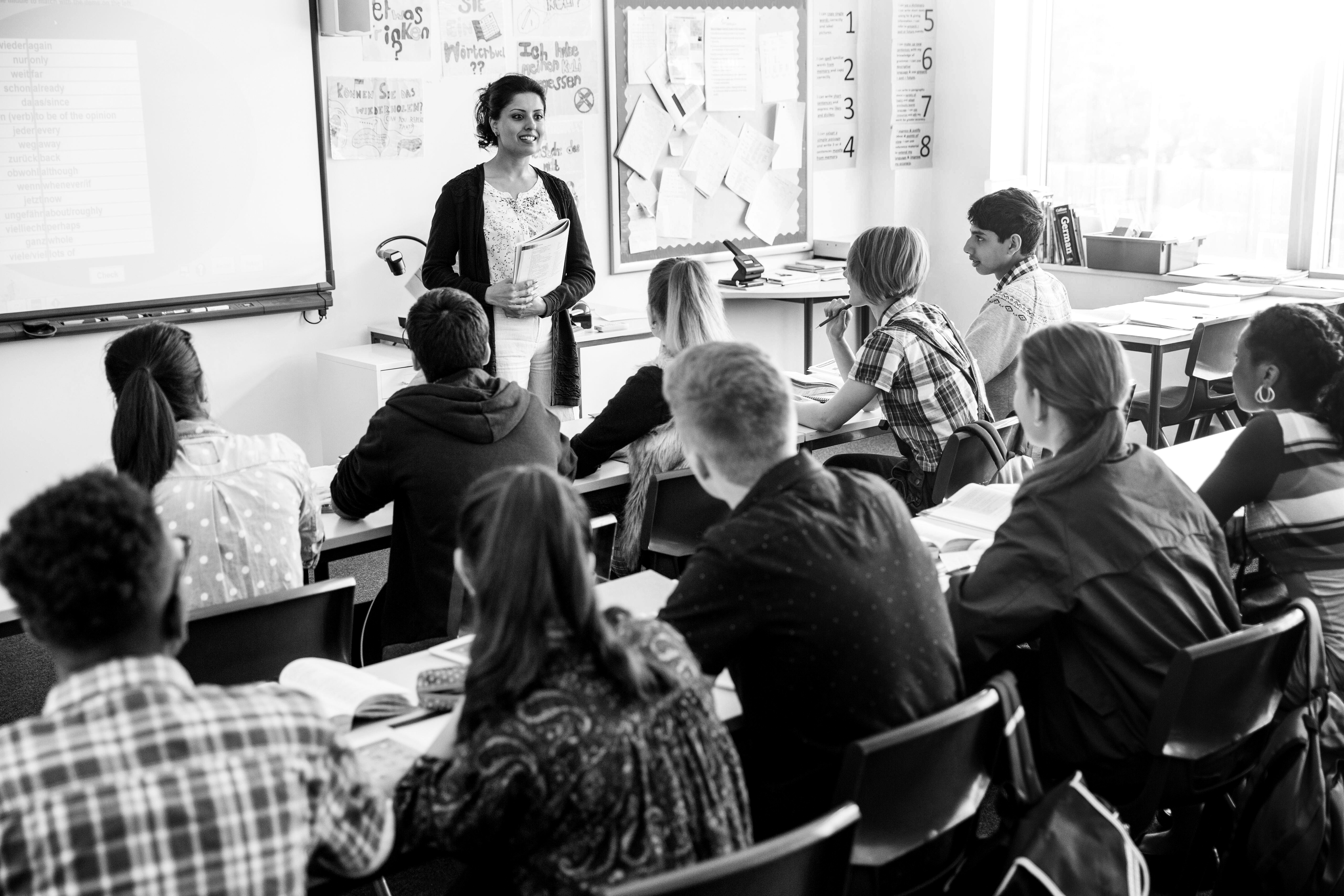 A teacher at the front of their class teaching a group of secondary school students