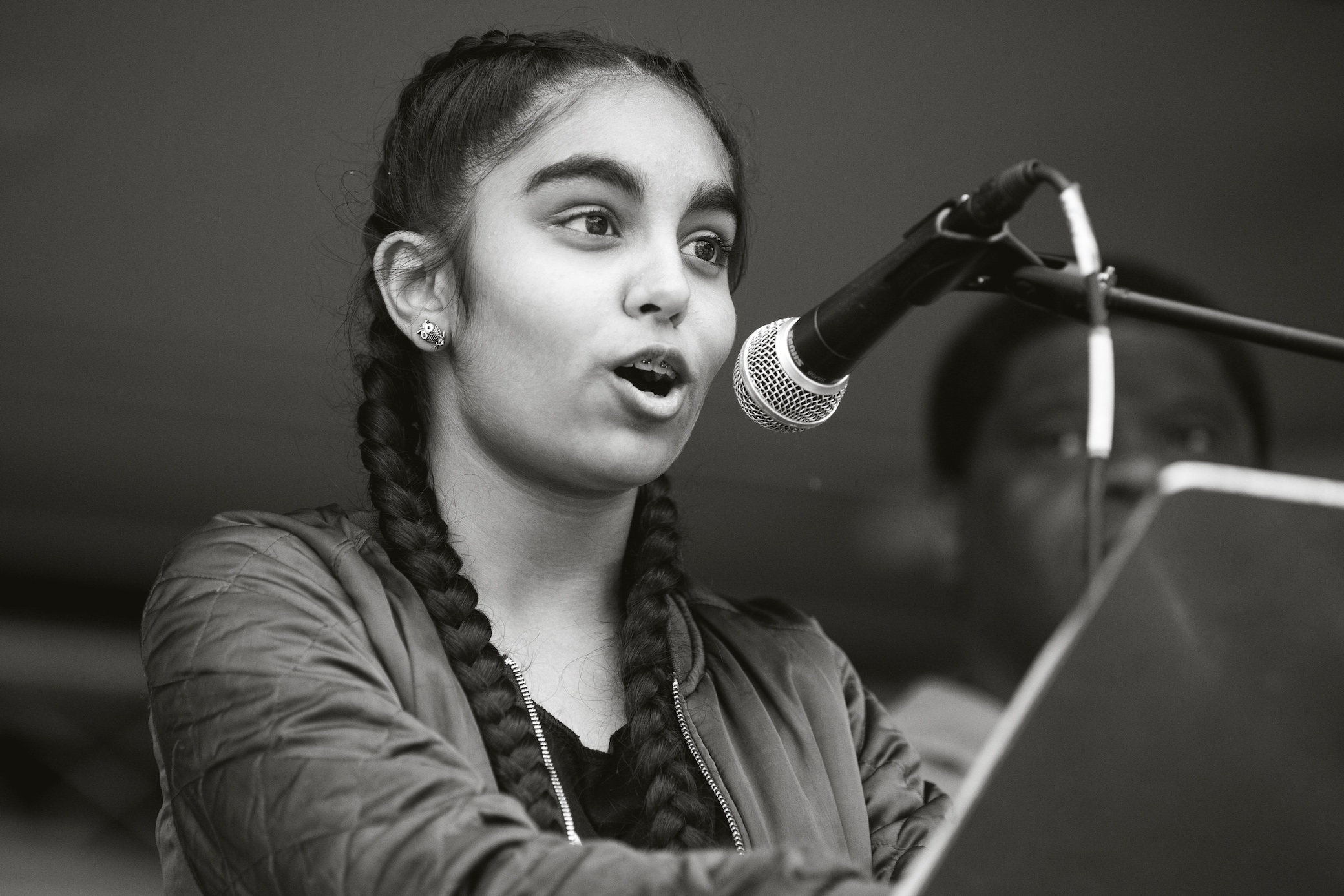 A young person speaking into a microphone at a lectern