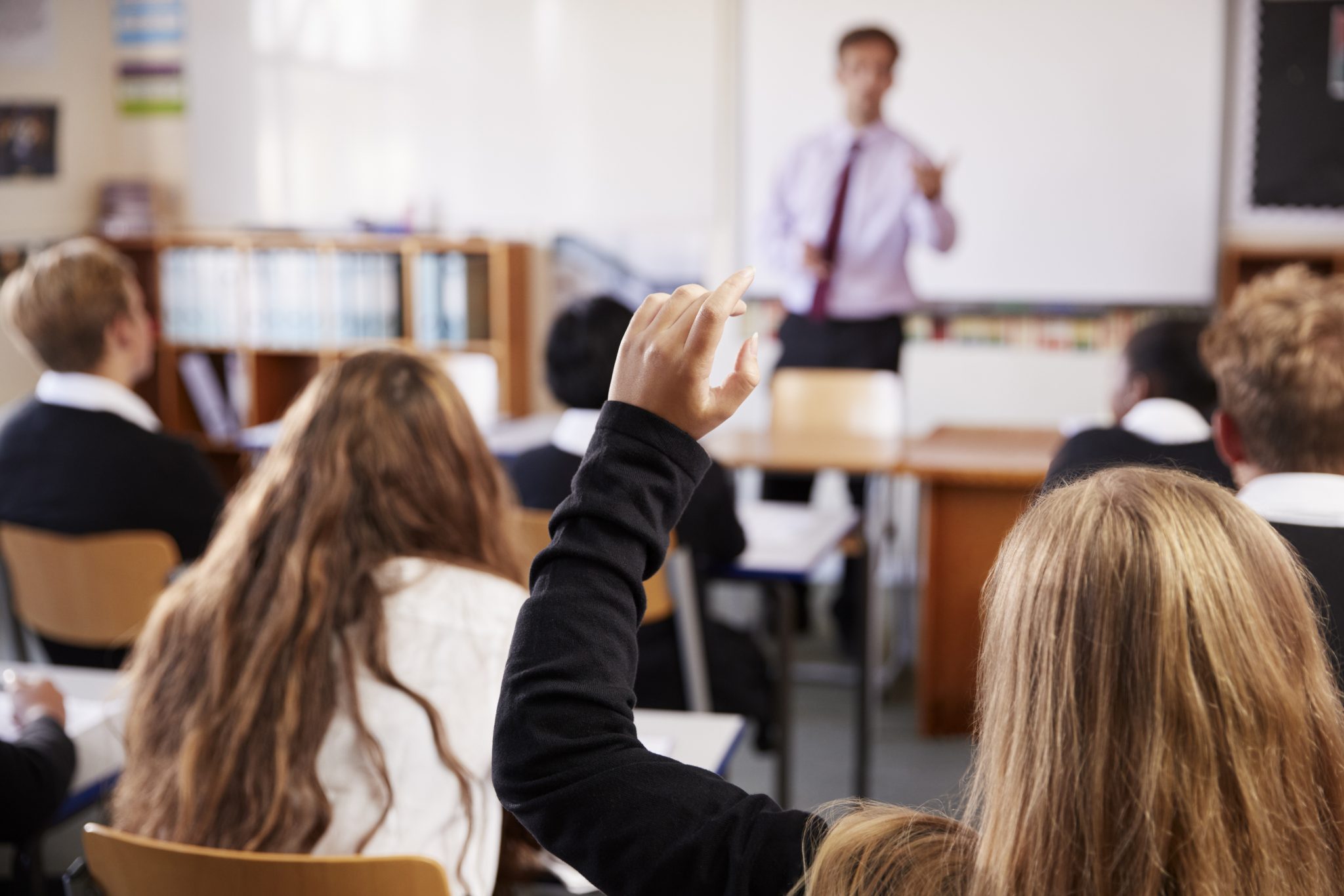 Pupil with hand up in class.