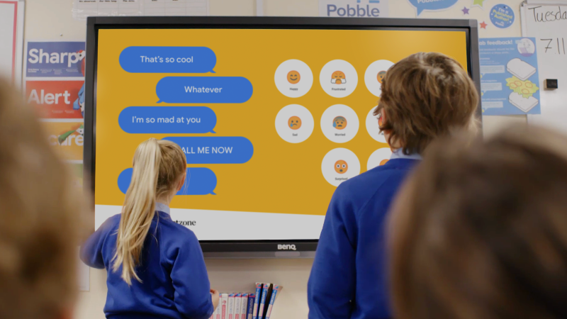 Two school children using interactive board.